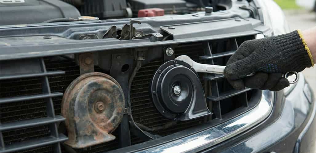 mecánico utilizando herramientas para reparar la bocina averiada de un automóvil."